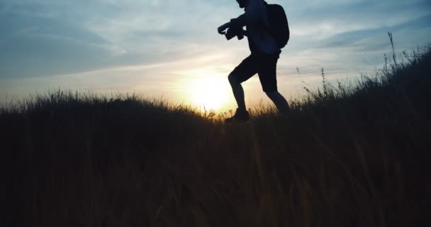 Путешествующий фотограф снимает летний закат на холме — стоковое видео