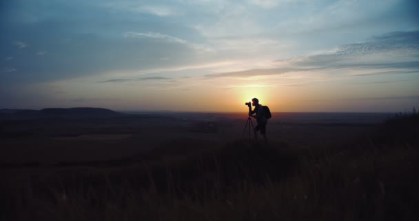 Fotógrafo tirando fotos do pôr do sol e usando tripé — Vídeo de Stock