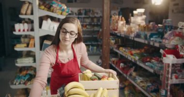 Kadın işçi dükkanda taze ürünleri kutulara dolduruyor.