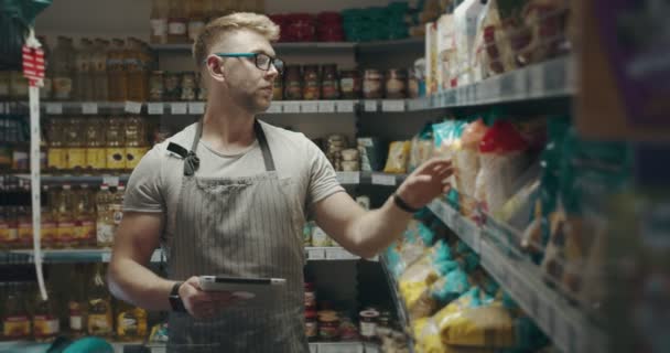 Gerente masculino usando tableta para inventario en tienda de comestibles — Vídeos de Stock