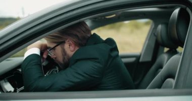 Siyah takım elbiseli bir adamın uzun araba sürerken dinlenmesi.