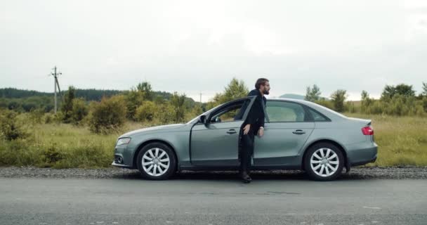 Bonito homem saindo do carro para relaxar depois de longa condução — Vídeo de Stock