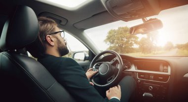 Yorgun iş adamı arabada dinleniyor.