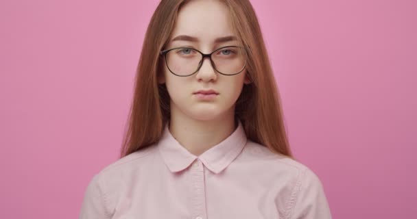 Charmantes Mädchen mit Brille lächelt über rosa Hintergrund — Stockvideo