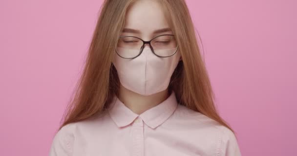 Mooi meisje in beschermende masker staande over roze achtergrond — Stockvideo