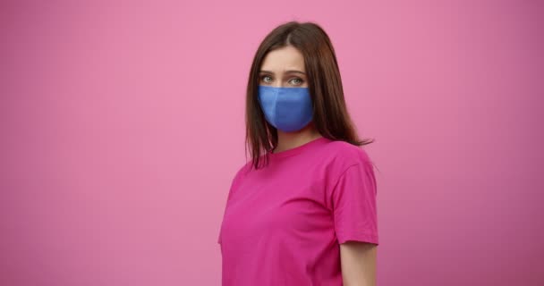 Teleurgesteld meisje in blauw masker poseren over roze achtergrond — Stockvideo