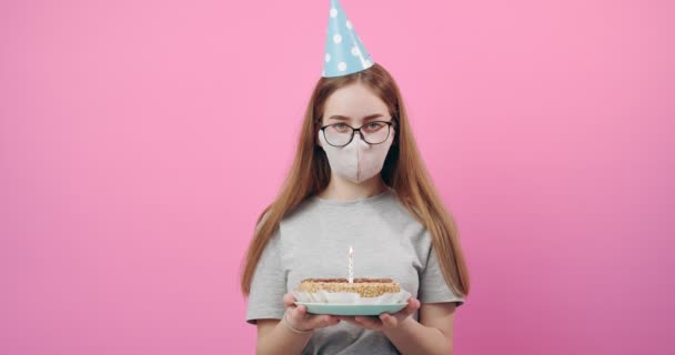 Chica en máscara médica y la tapa festiva celebración de pastel de cumpleaños — Vídeos de Stock