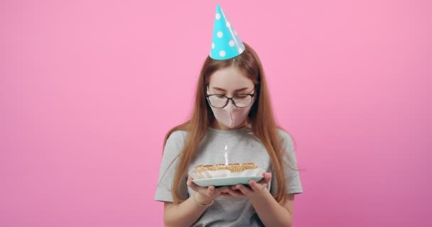 Cumpleaños chica soplando la vela en la torta en máscara médica — Vídeo de stock