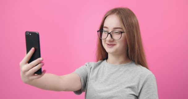Улыбающаяся женщина в очках с видеочатом на смартфоне — стоковое видео