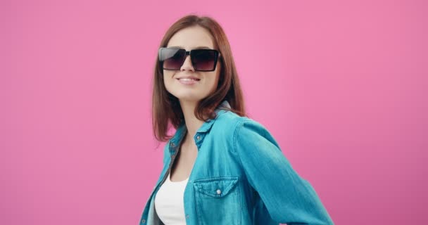 Okouzlující dívka ve slunečních brýlích a džínové košili pózuje ve studiu — Stock video