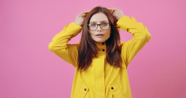 Mujer con gafas y impermeable amarillo posando en cámara — Vídeos de Stock