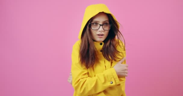 Гарненька леді відчуває холод під час носіння жовтого плаща — стокове відео