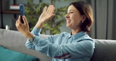 Mutlu kadın evde video görüşmesi için akıllı telefon kullanıyor.