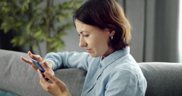 Vrouw besteedt vrije tijd thuis en met behulp van smartphone — Stockvideo