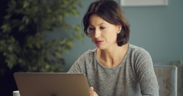 Серйозна жінка розмовляє через відео чат на ноутбуці — стокове відео