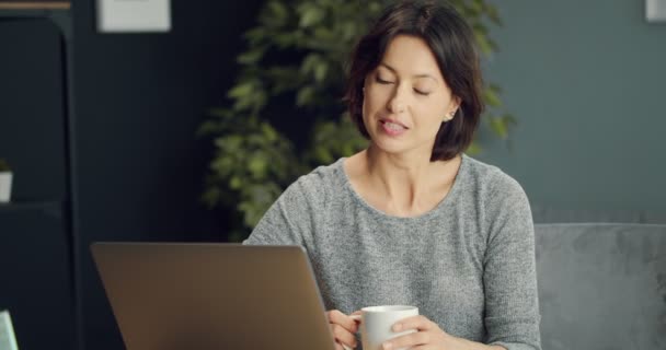 Güzel bir kadın dizüstü bilgisayarda görüntülü konuşma yapıyor. — Stok video