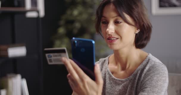 Kvinna som använder smartphone och kreditkort för online-betalningar — Stockvideo