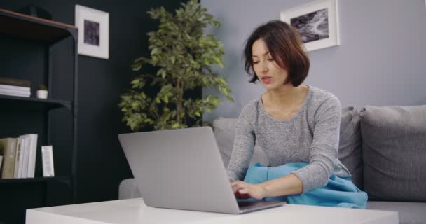 Evde boş zamanlarında dizüstü bilgisayar kullanan rahat bir kadın.. — Stok video