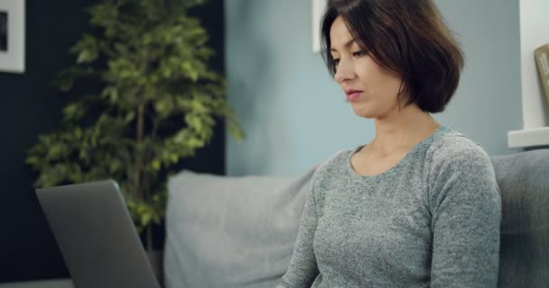 Mulher encantadora relaxante no sofá com laptop moderno — Vídeo de Stock