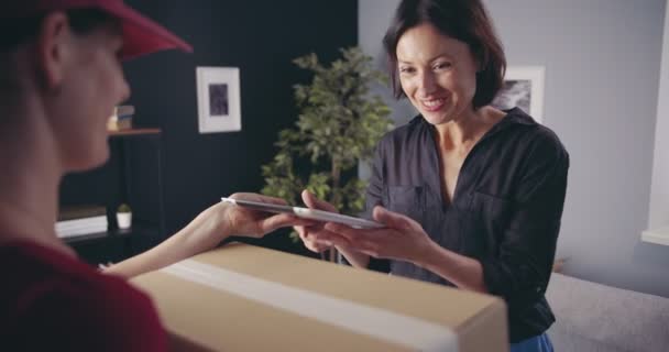 Vrolijke vrouw die tekent op tablet voor het ontvangen van pakket — Stockvideo