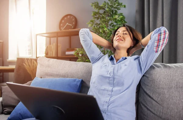 Charmante Dame entspannt sich auf der Couch bei der Fernbedienung am Laptop — Stockfoto