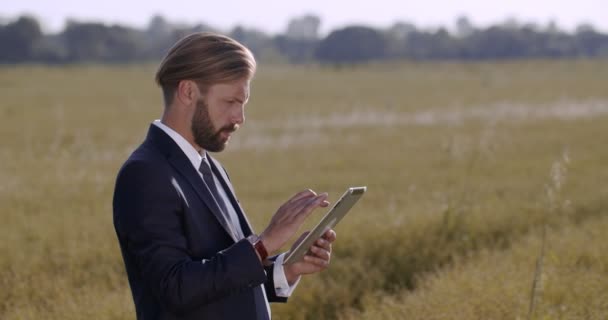 Agricultor en traje con tableta digital que inspecciona la cosecha joven — Vídeos de Stock