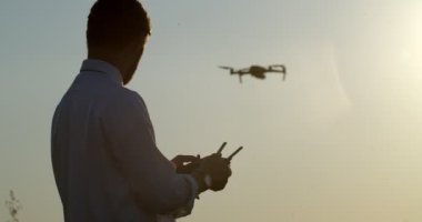 Resmi kıyafetli yakışıklı çiftçi tarlada drone kullanıyor.