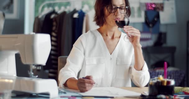 Hermosa mujer disfrutando del vino tinto mientras dibuja bocetos — Vídeo de stock