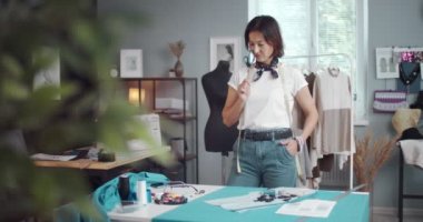 Terzi elinde makasla mavi kumaşa bakıyor.