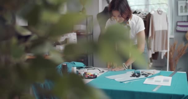 Ontwerper met schaar voor het knippen van blauwe stof in atelier — Stockvideo