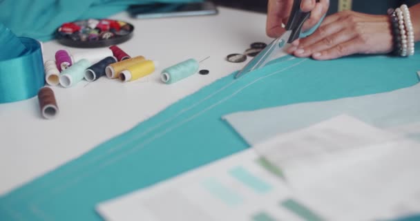 Close up van vrouwelijke ontwerper snijden blauwe doek op de werkplek — Stockvideo
