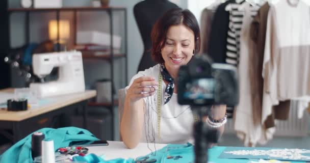 Felice signora mostrando accessori per il cucito durante la registrazione video — Video Stock