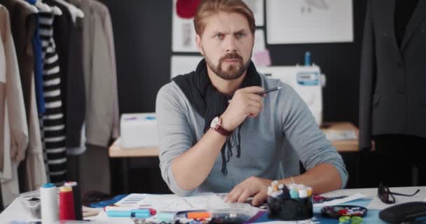 Designer masculino atencioso trabalhando com esboços no estúdio — Vídeo de Stock