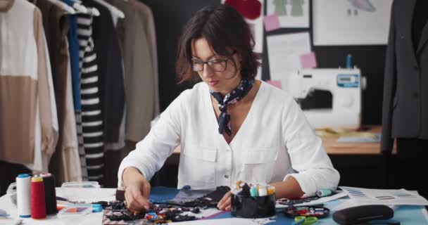 Vrouwelijke ontwerper werkt met naaiaccessoires op atelier — Stockvideo