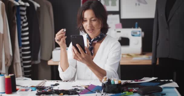 Designer sorrindo ter vídeo chat no smartphone no trabalho — Vídeo de Stock