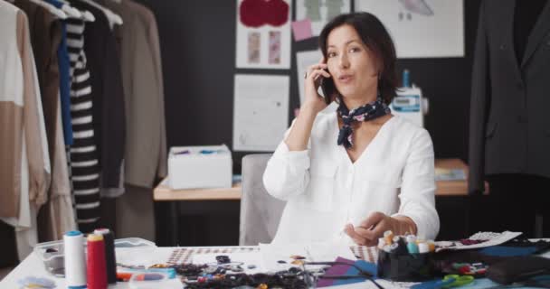 Hermoso diseñador teniendo conversación en el teléfono inteligente en el trabajo — Vídeos de Stock