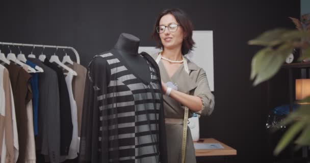 Женщина-кутюрье разрабатывает модное платье на манекене — стоковое видео