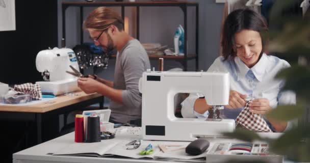 Hombre y mujer sonrientes diseñando ropa en el taller — Vídeos de Stock