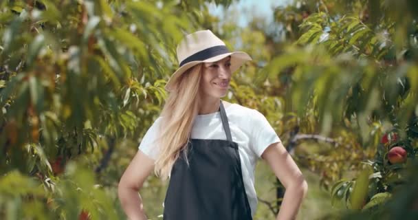 Femme en chapeau d'été posant sur la caméra au jardin de pêche — Video
