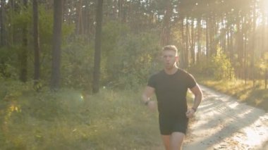 Yaz günbatımında doğada koşan genç bir atletik.