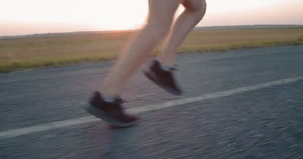 Low angle view of male athlete jogging on paved road — Stock Video