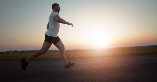 Side view of sportsman running during summer sunset — Stock Video