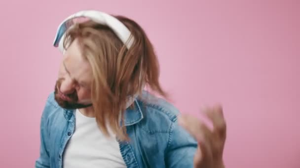 Radosny mężczyzna w słuchawkach bezprzewodowych tańczący w studio — Wideo stockowe