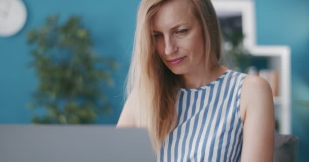 Очаровательная женщина сидит дома и работает на ноутбуке — стоковое видео