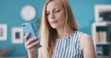 Güzel bir kadın evde dinleniyor ve akıllı telefon kullanıyor.