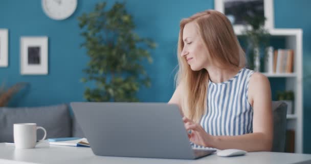 Surprised woman using smartphone and laptop for work — Stock Video