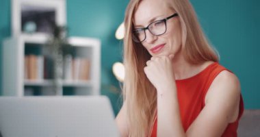 İş için evde dizüstü bilgisayar kullanan mutlu bir kadın.