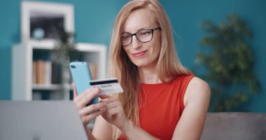 Mutlu kadın kanepede oturuyor ve online alışveriş yapıyor.