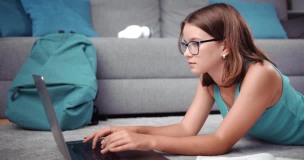 Mujer adolescente en gafas que estudia en el ordenador portátil en casa — Vídeos de Stock