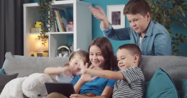 Empat anak cantik melambaikan tangan saat video chat di tablet digital — Stok Video